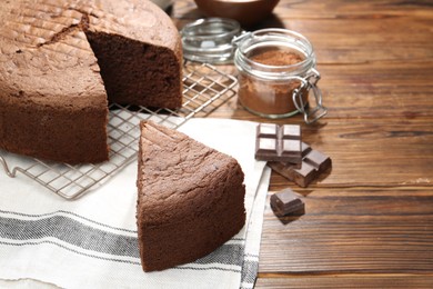 Photo of Cut chocolate sponge cake on wooden table, closeup