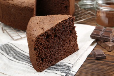 Photo of Piece of tasty chocolate sponge cake on wooden table, closeup