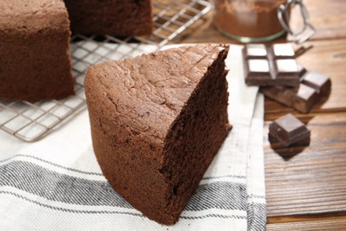 Photo of Piece of tasty chocolate sponge cake on wooden table, closeup