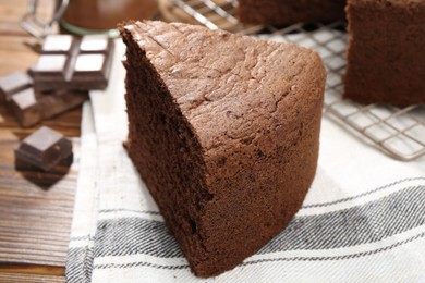 Photo of Piece of tasty chocolate sponge cake on wooden table, closeup