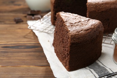 Photo of Piece of tasty chocolate sponge cake on wooden table, closeup