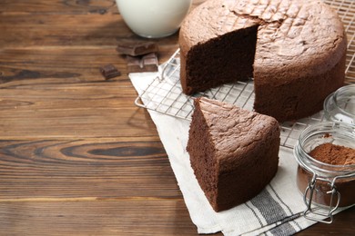 Photo of Cut chocolate sponge cake on wooden table. Space for text