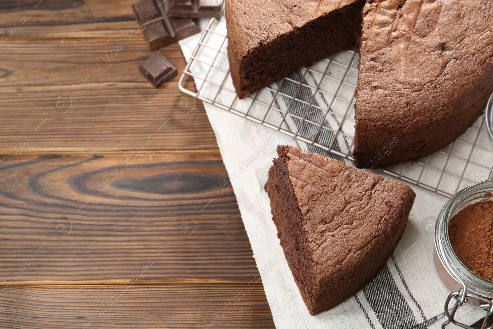 Photo of Cut chocolate sponge cake on wooden table, above view. Space for text