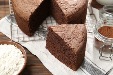 Photo of Cut chocolate sponge cake on wooden table, closeup