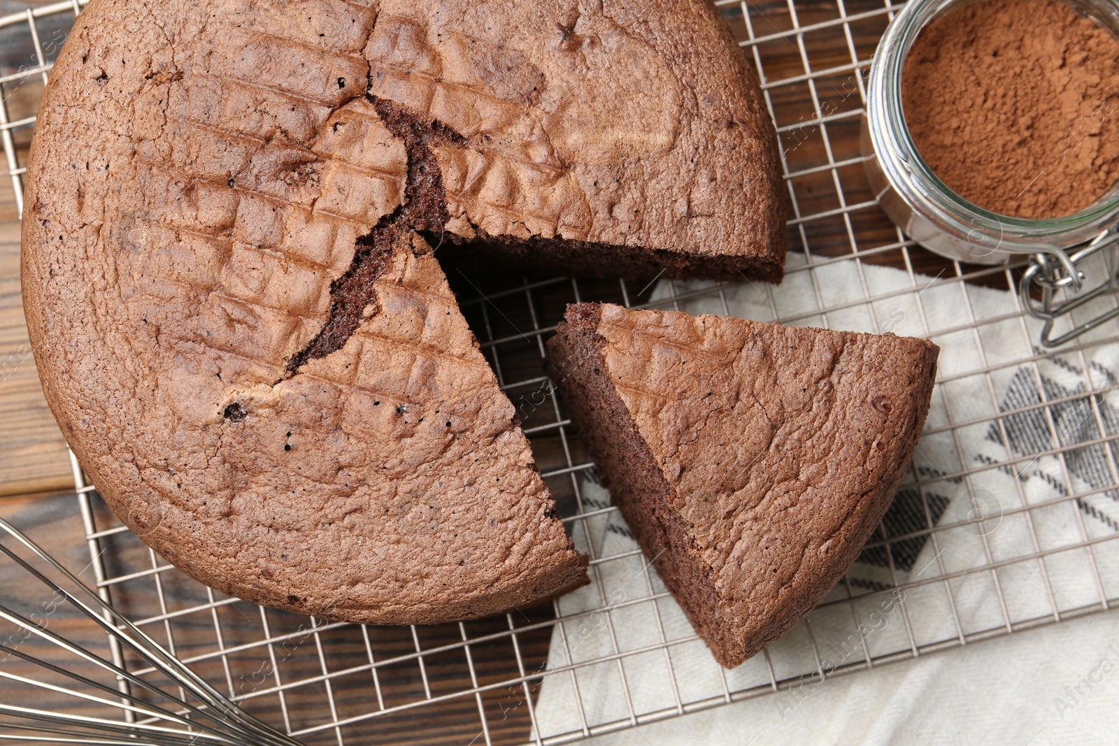 Photo of Cut chocolate sponge cake and cocoa powder on wooden table, top view