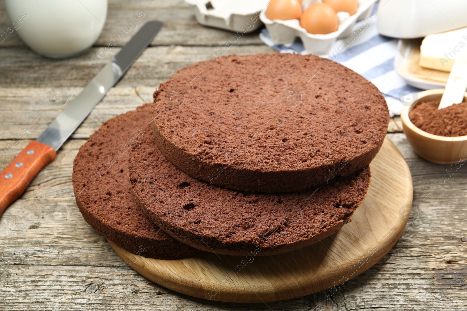 Photo of Cut chocolate sponge cake and ingredients on wooden table