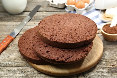 Photo of Cut chocolate sponge cake and ingredients on wooden table