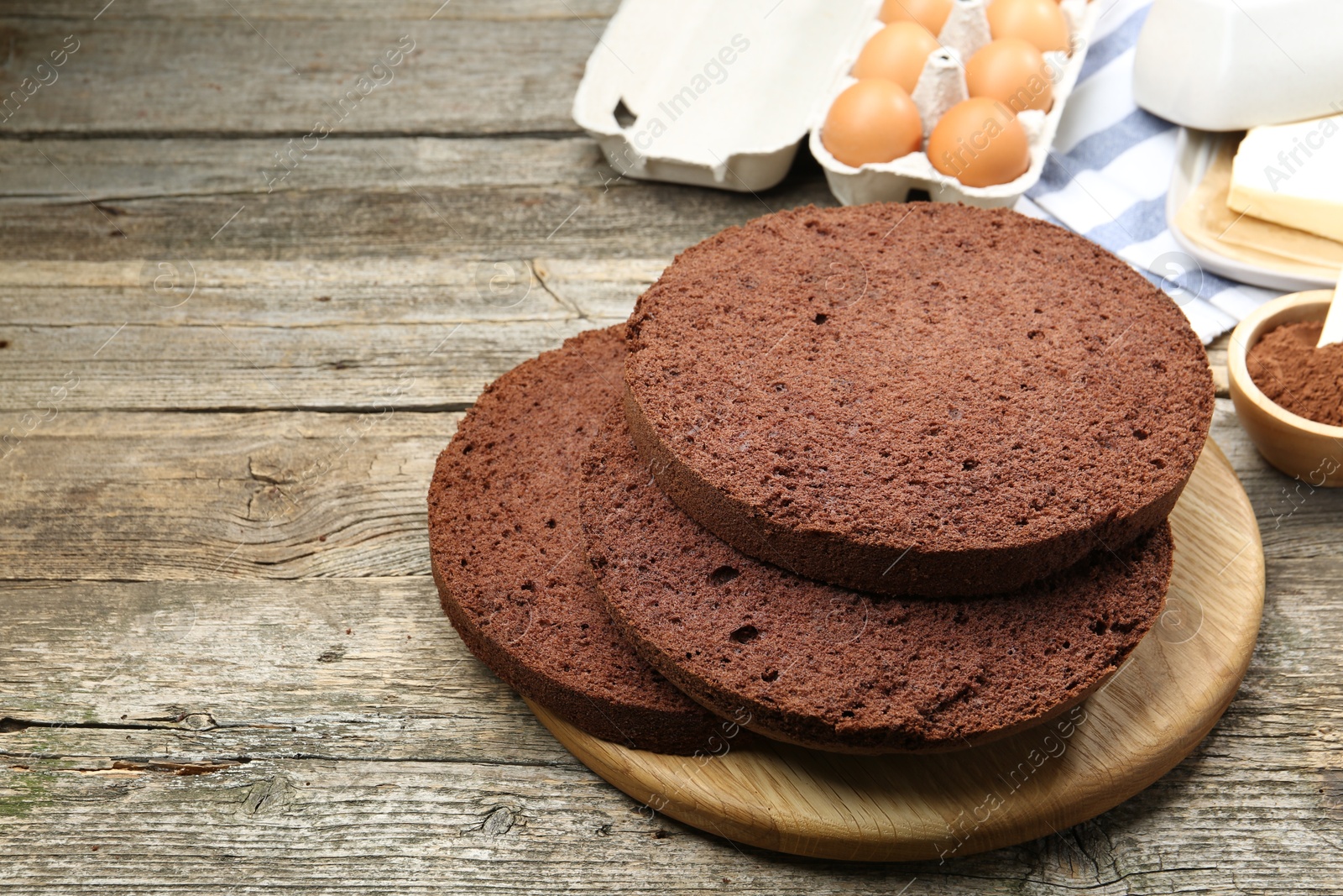 Photo of Cut chocolate sponge cake and ingredients on wooden table. Space for text