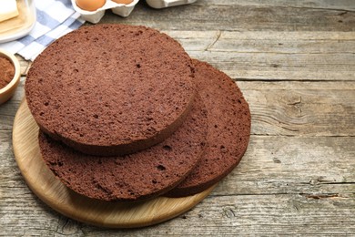 Photo of Cut chocolate sponge cake and ingredients on wooden table. Space for text