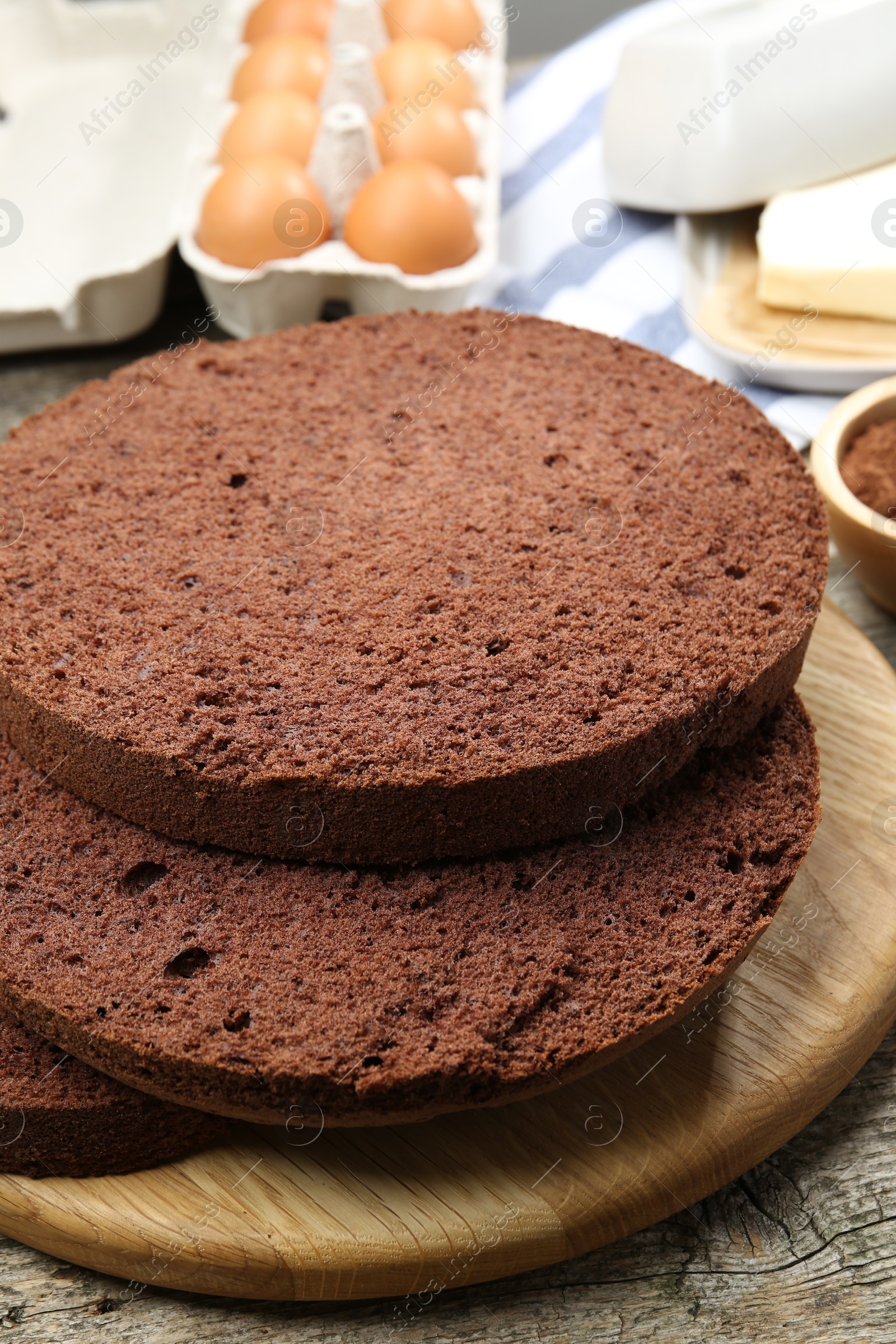 Photo of Cut chocolate sponge cake and ingredients on wooden table, closeup