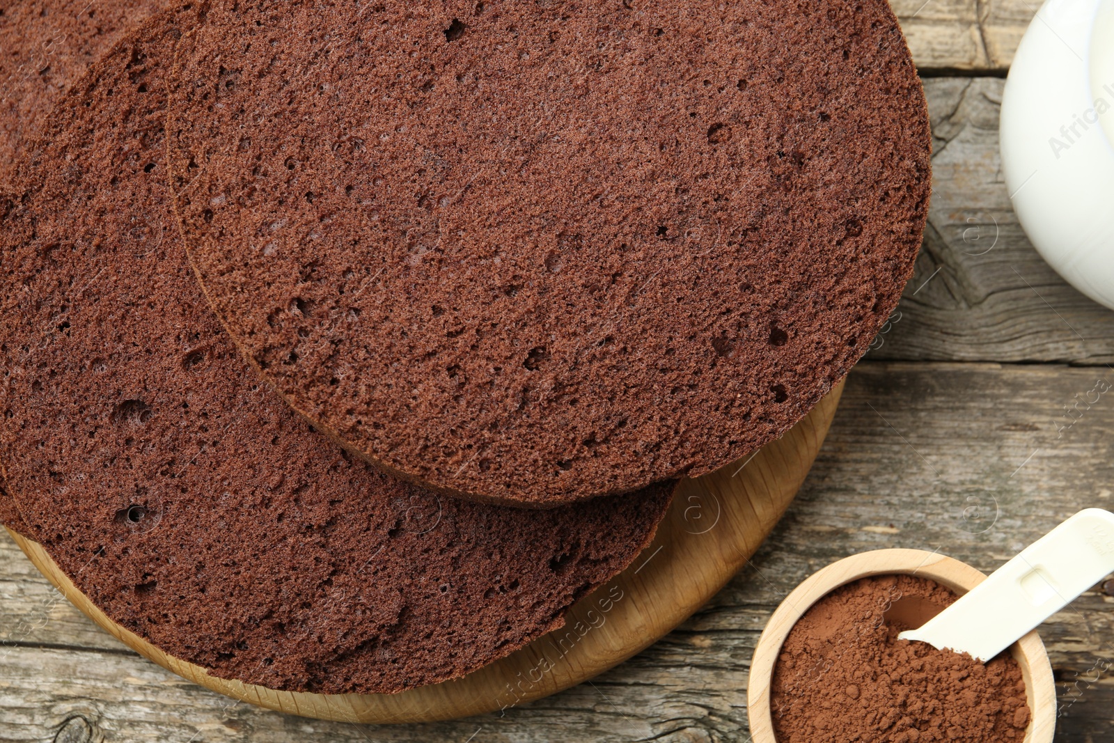 Photo of Cut chocolate sponge cake and cocoa powder on wooden table, top view