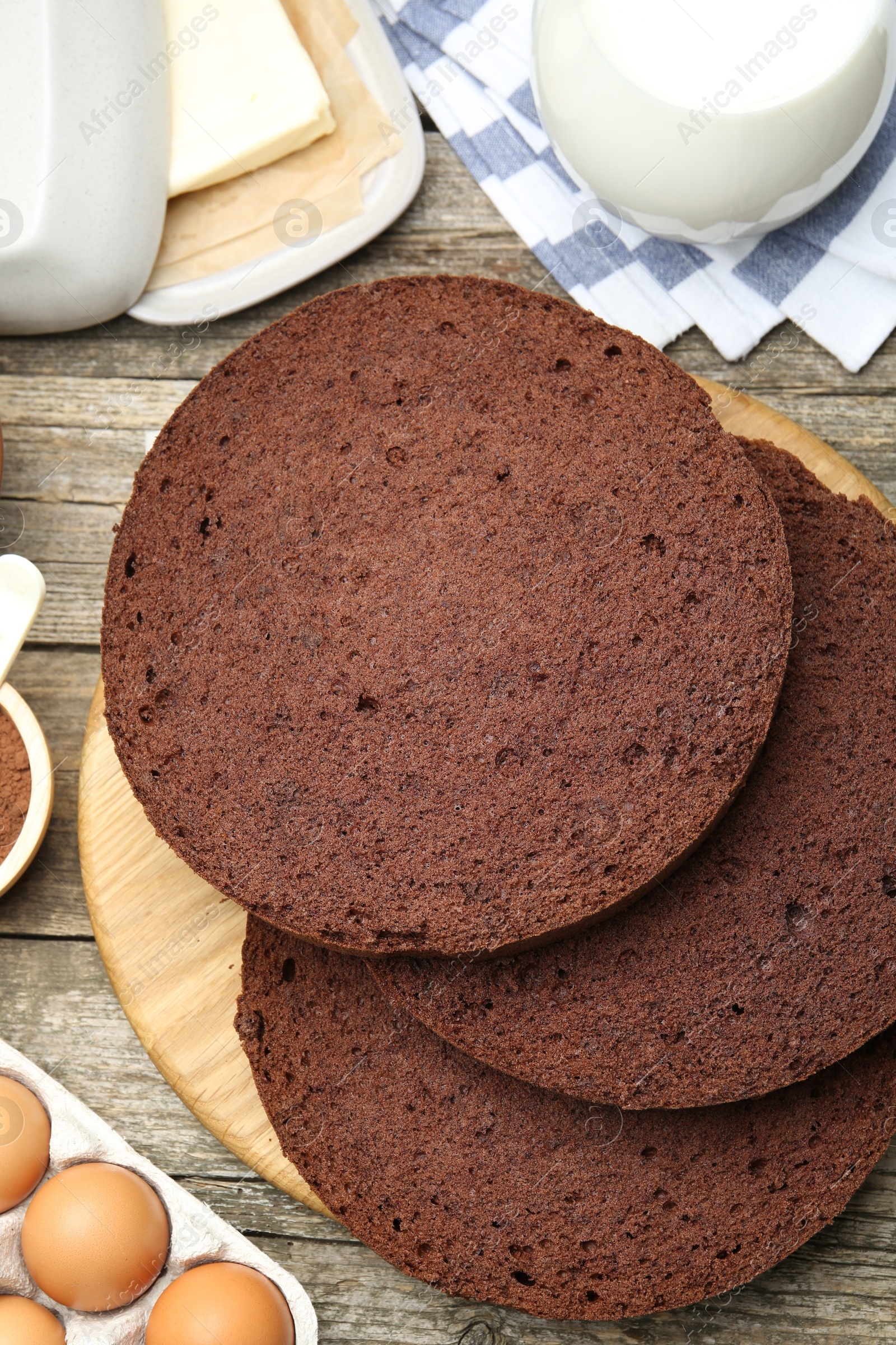 Photo of Cut chocolate sponge cake and ingredients on wooden table, flat lay