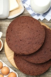 Photo of Cut chocolate sponge cake and ingredients on wooden table, flat lay