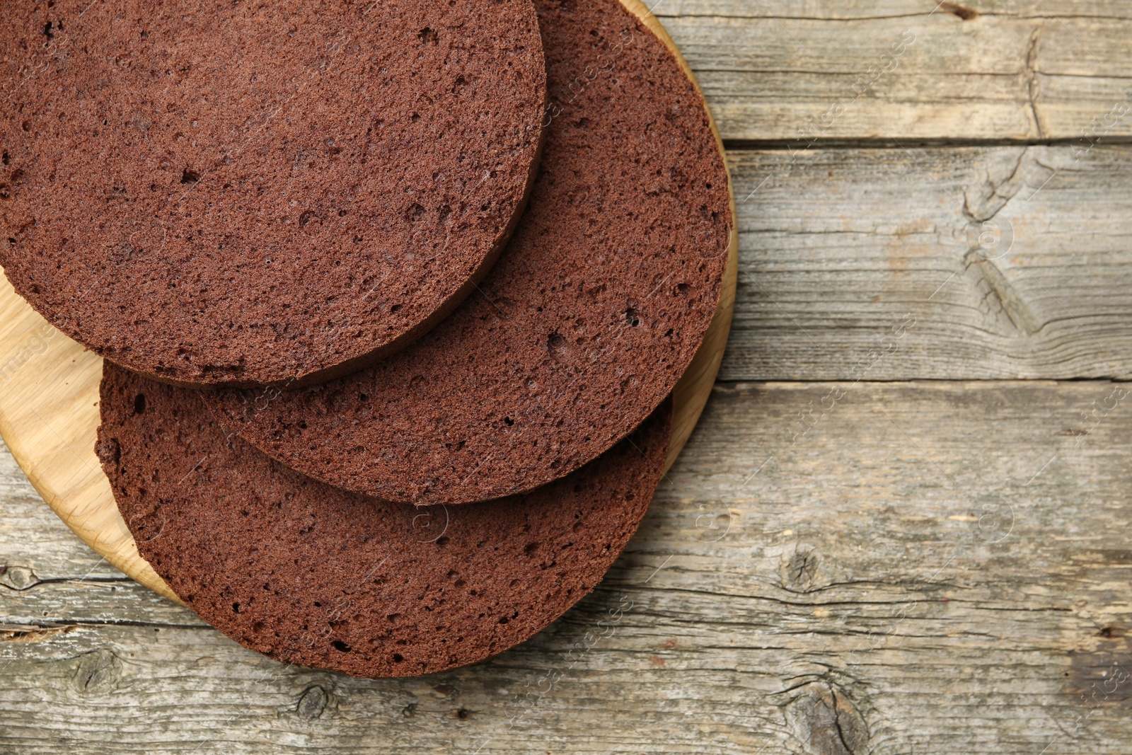 Photo of Cut chocolate sponge cake on wooden table, top view. Space for text