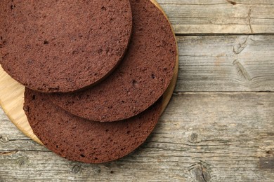 Photo of Cut chocolate sponge cake on wooden table, top view. Space for text