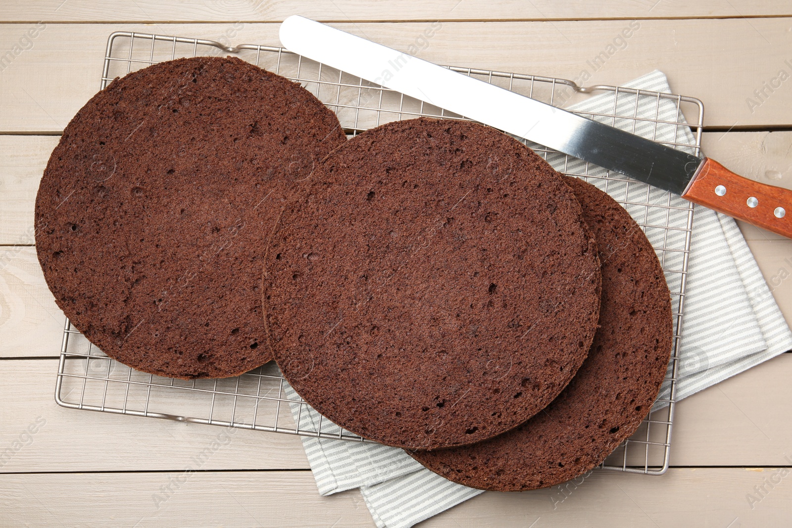 Photo of Cut chocolate sponge cake and knife on wooden table, top view