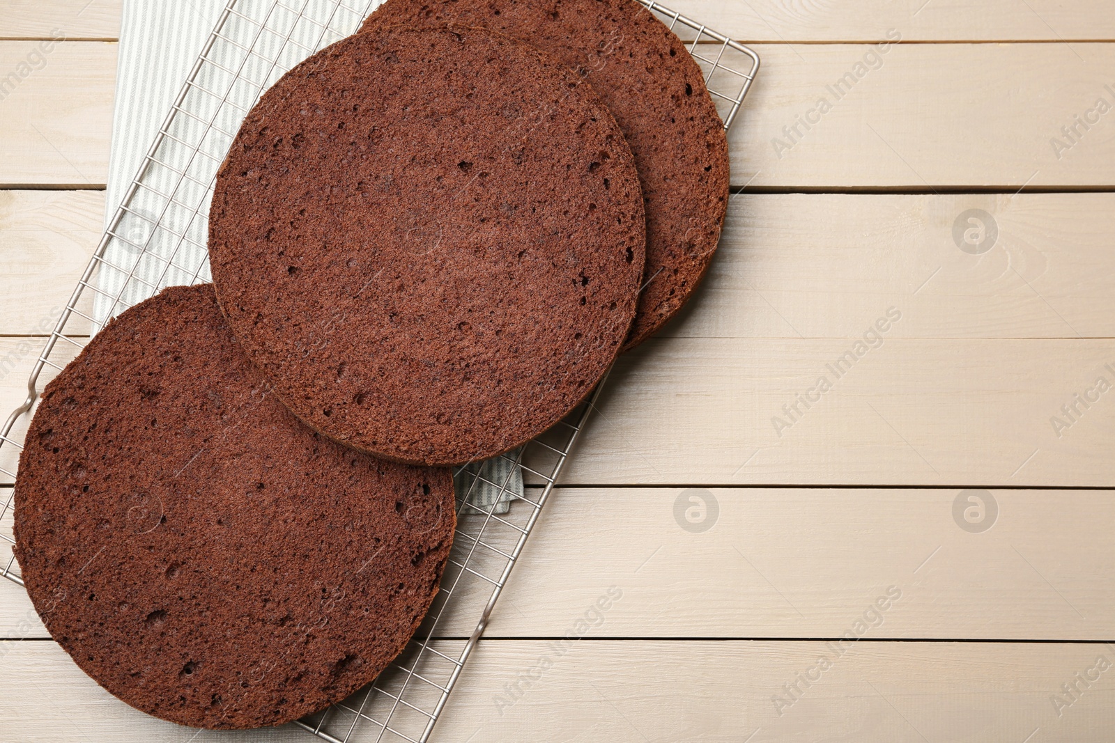 Photo of Cut chocolate sponge cake on wooden table, top view. Space for text