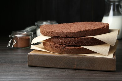 Photo of Cut chocolate sponge cake and ingredients on wooden table