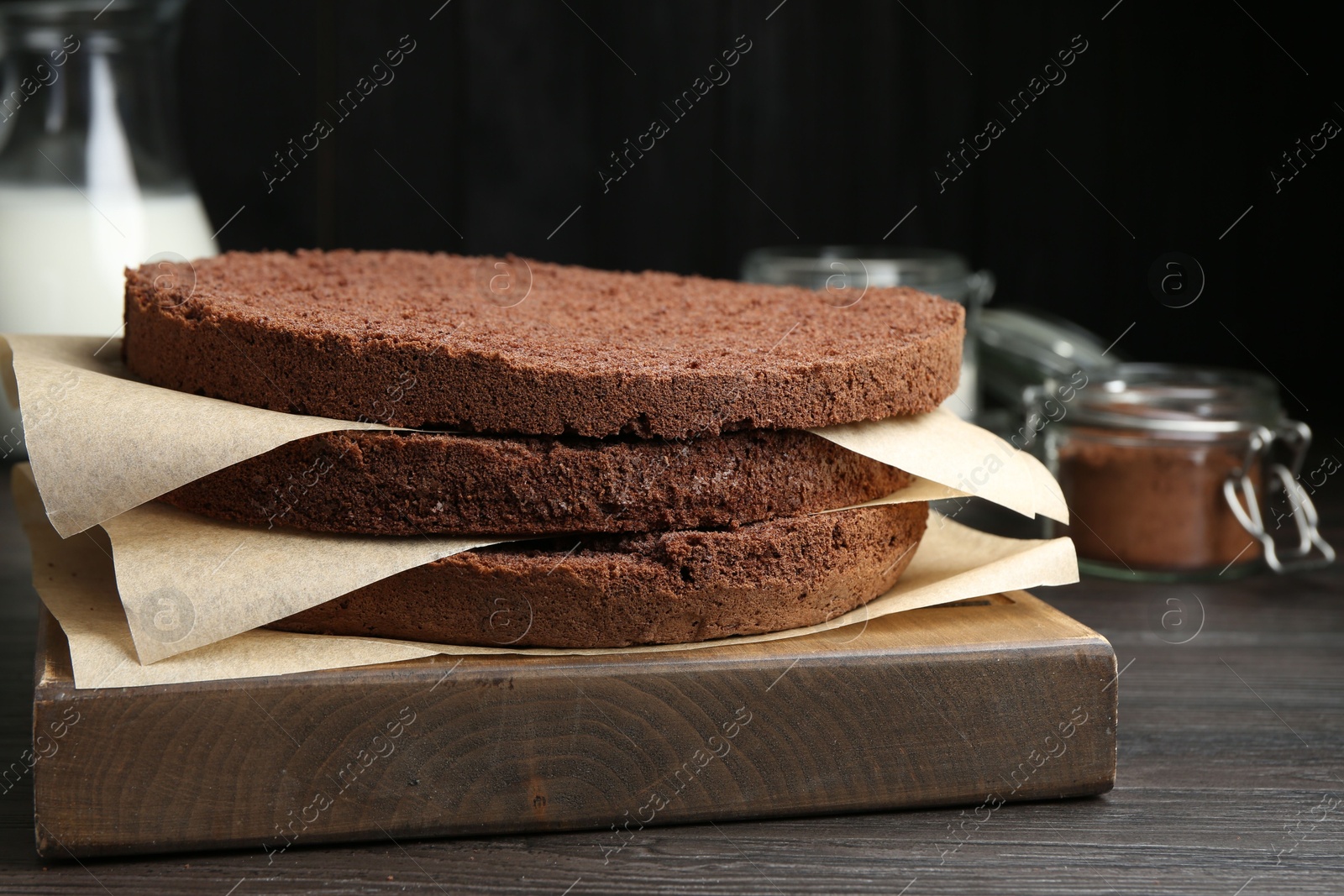 Photo of Cut chocolate sponge cake and ingredients on wooden table, closeup