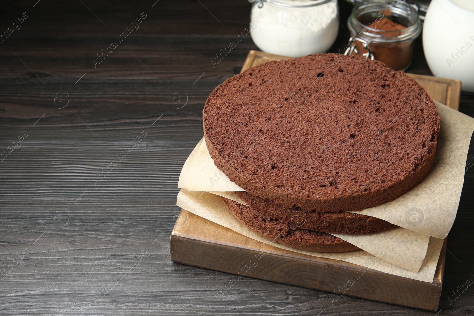 Photo of Cut chocolate sponge cake and ingredients on wooden table. Space for text