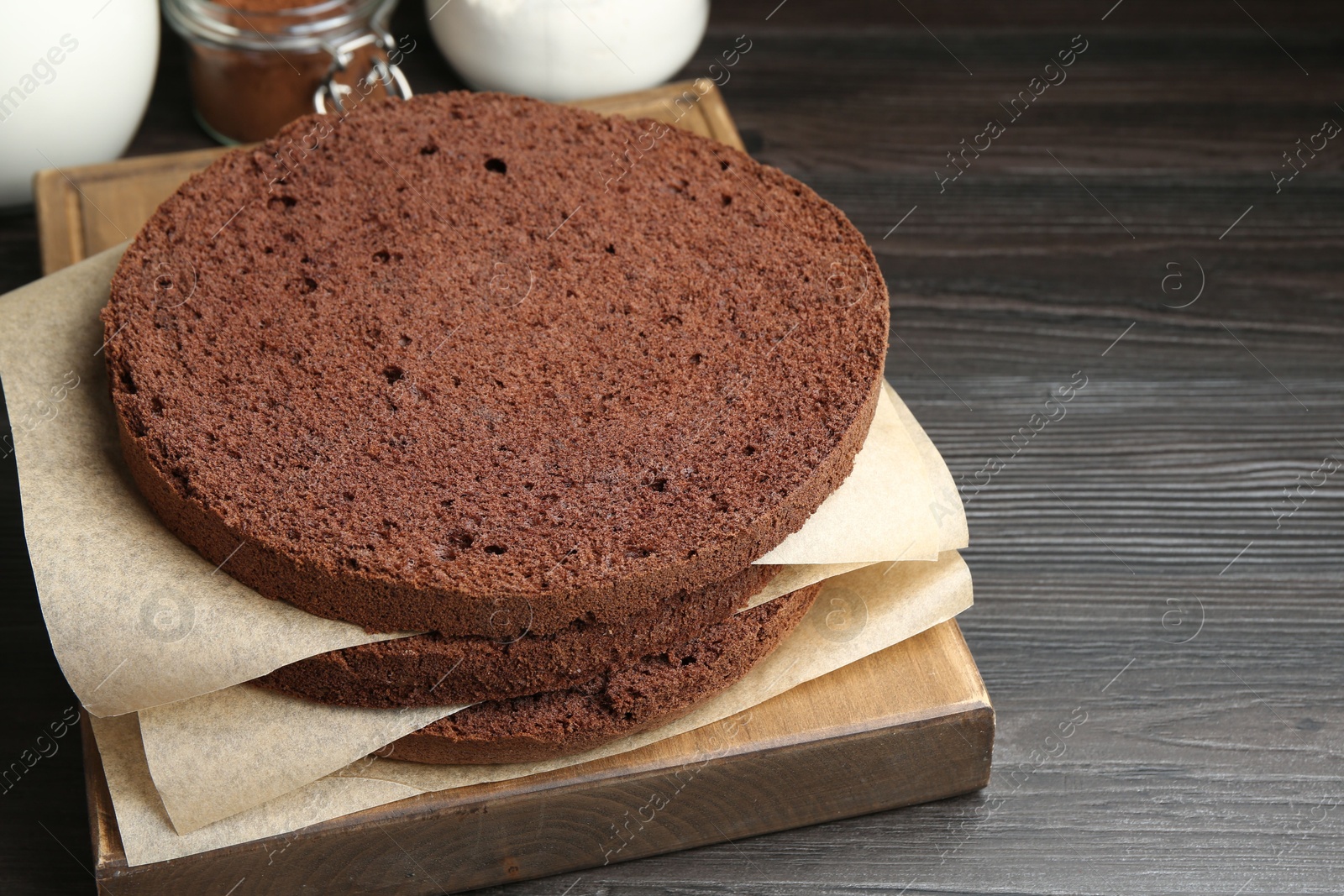 Photo of Cut chocolate sponge cake and ingredients on wooden table, closeup