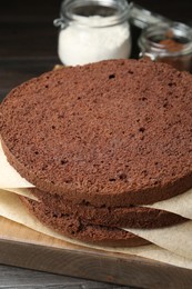 Photo of Cut chocolate sponge cake and ingredients on wooden table, closeup