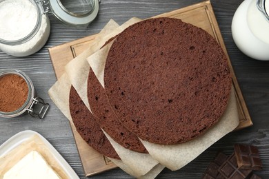 Photo of Cut chocolate sponge cake and ingredients on wooden table, flat lay