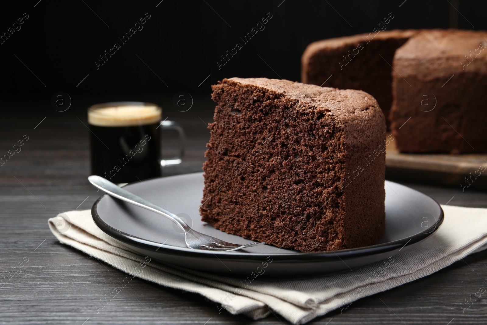 Photo of Piece of tasty chocolate sponge cake served on wooden table, closeup