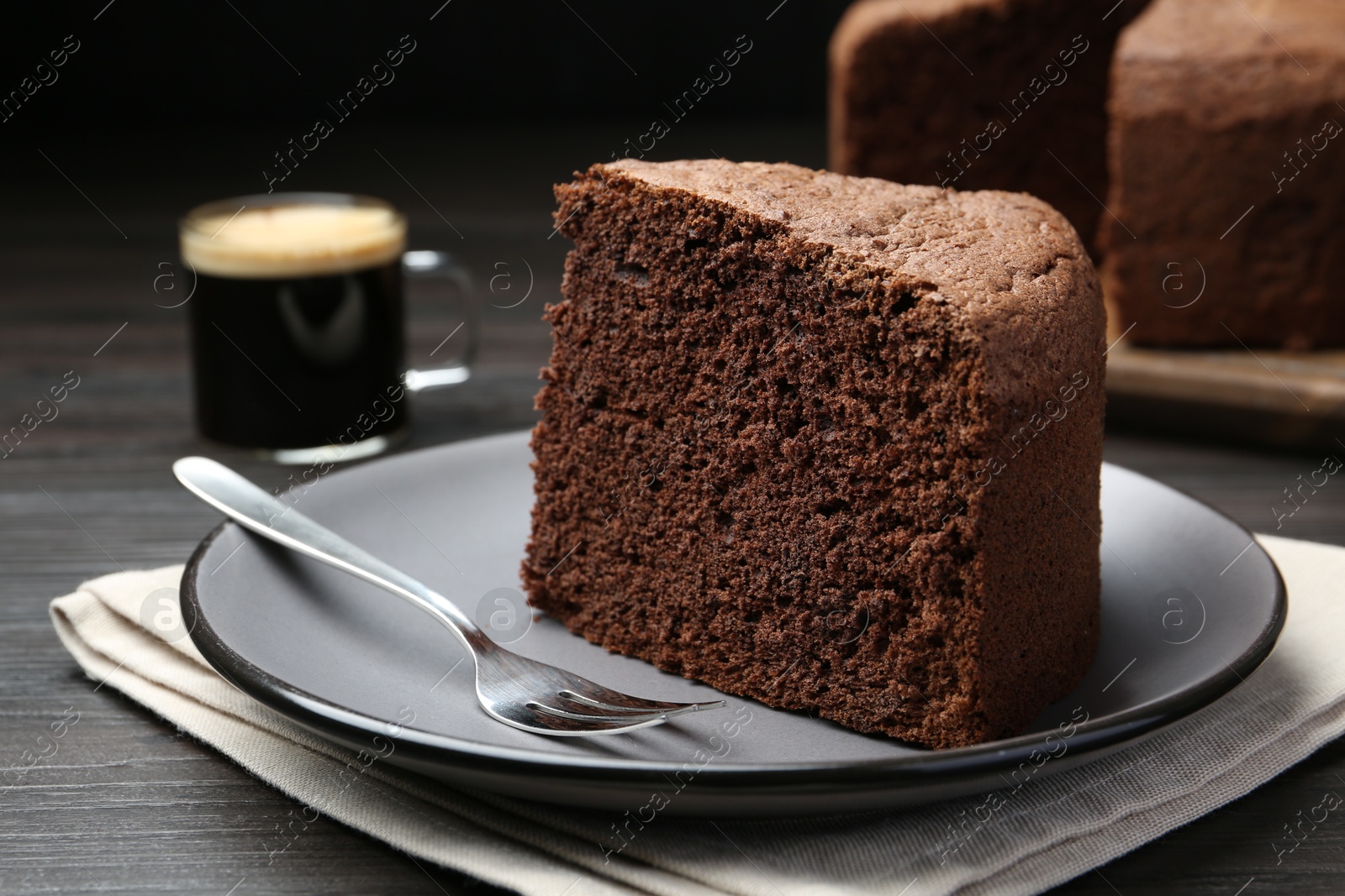 Photo of Piece of tasty chocolate sponge cake served on wooden table, closeup