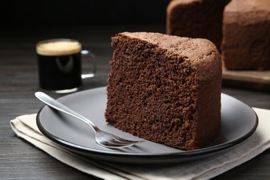 Photo of Piece of tasty chocolate sponge cake served on wooden table, closeup