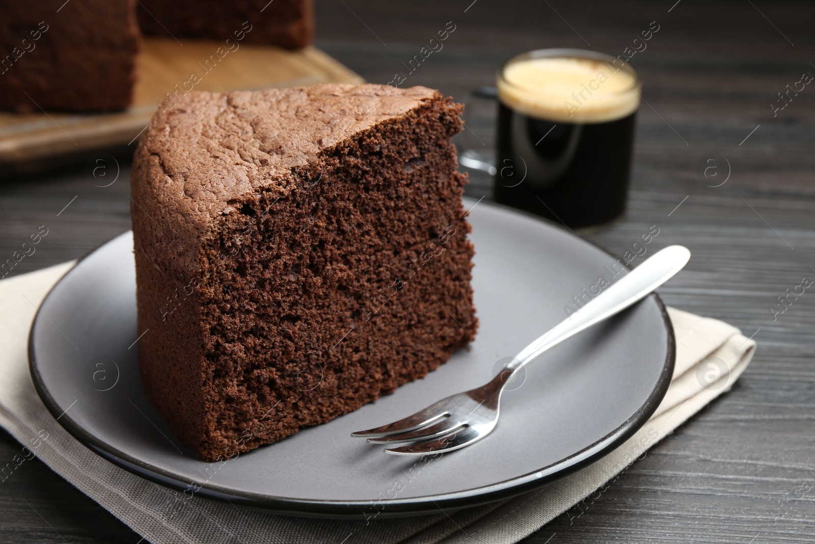 Photo of Piece of tasty chocolate sponge cake served on wooden table, closeup