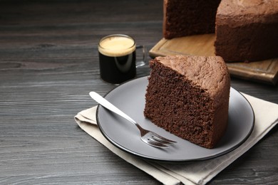 Photo of Piece of tasty chocolate sponge cake served on wooden table, closeup