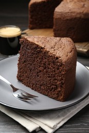 Photo of Piece of tasty chocolate sponge cake served on wooden table, closeup