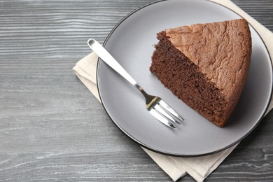 Photo of Piece of tasty chocolate sponge cake served on wooden table, above view