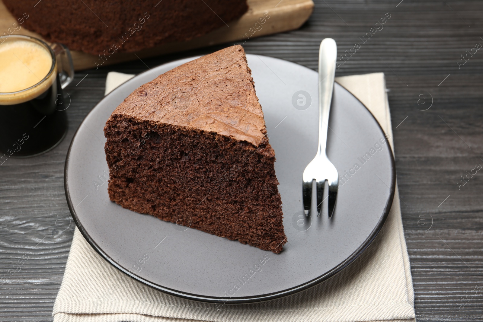 Photo of Piece of tasty chocolate sponge cake served on wooden table, closeup