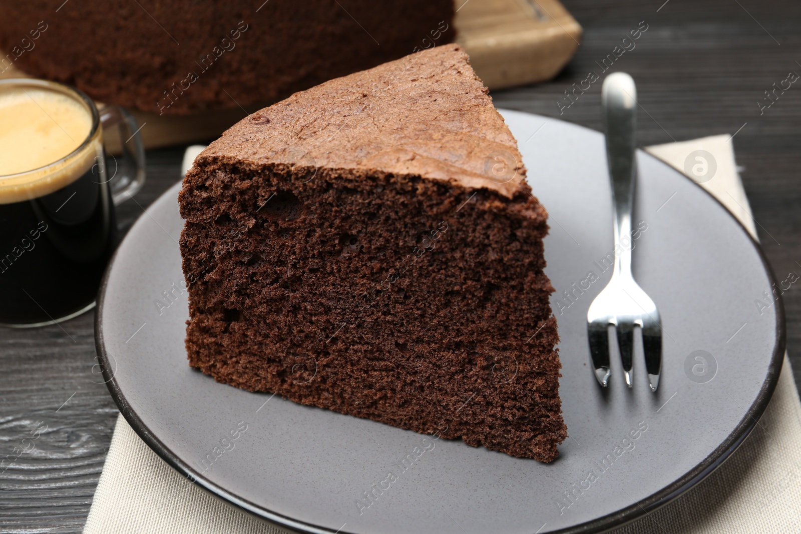 Photo of Piece of tasty chocolate sponge cake served on wooden table, closeup