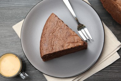 Photo of Piece of tasty chocolate sponge cake served on wooden table, flat lay