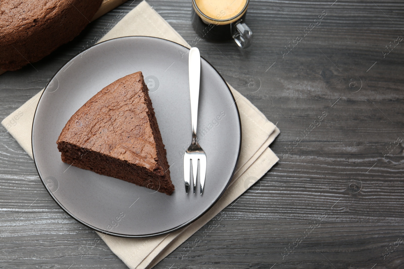 Photo of Piece of tasty chocolate sponge cake served on wooden table, flat lay