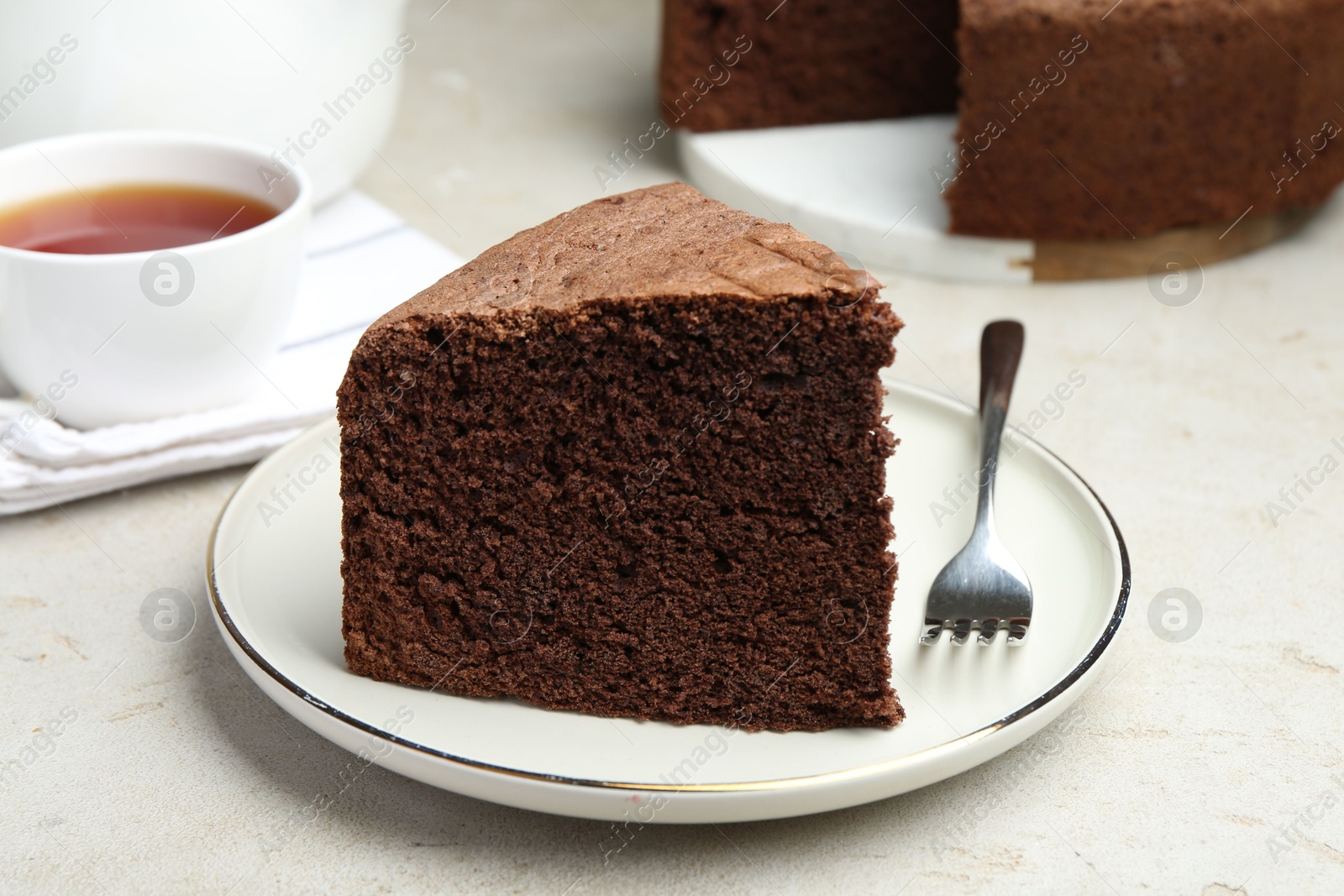 Photo of Piece of tasty chocolate sponge cake served on light table, closeup