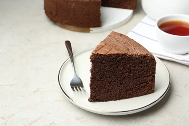 Photo of Piece of tasty chocolate sponge cake served on light table, closeup