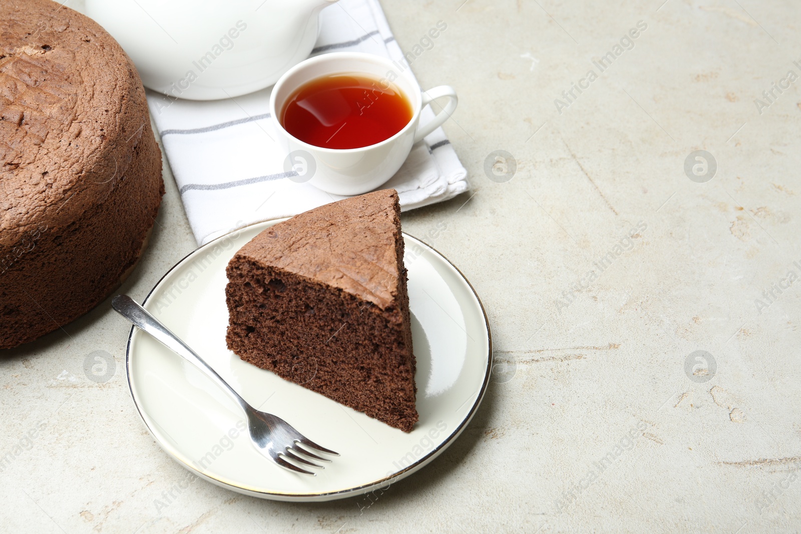 Photo of Piece of tasty chocolate sponge cake served on light table. Space for text