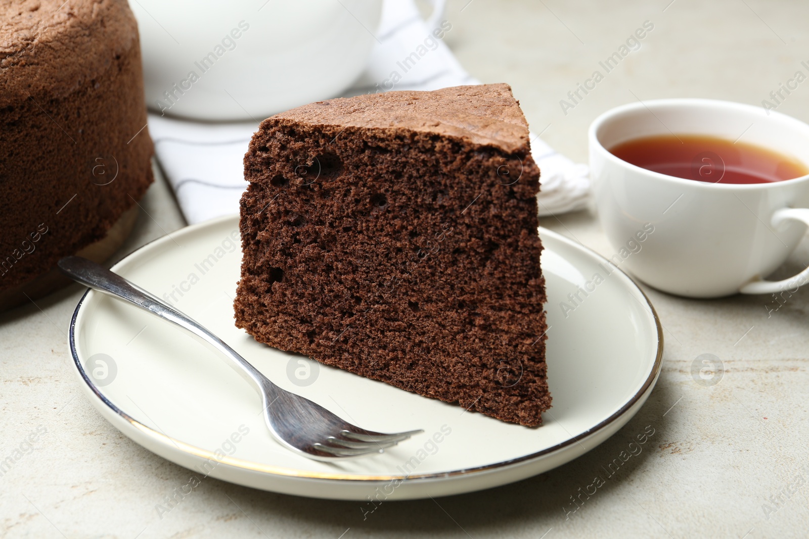 Photo of Piece of tasty chocolate sponge cake served on light table, closeup