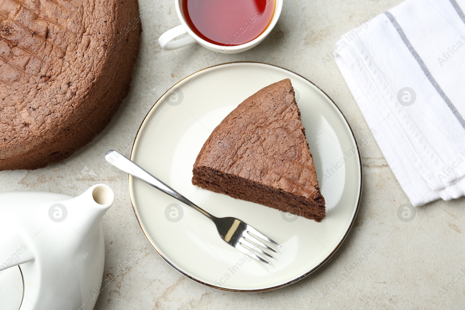 Photo of Piece of tasty chocolate sponge cake served on light table, flat lay