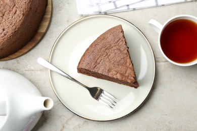 Photo of Piece of tasty chocolate sponge cake served on light table, flat lay