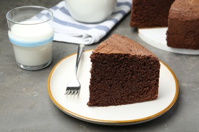 Photo of Piece of tasty chocolate sponge cake served on grey table, closeup