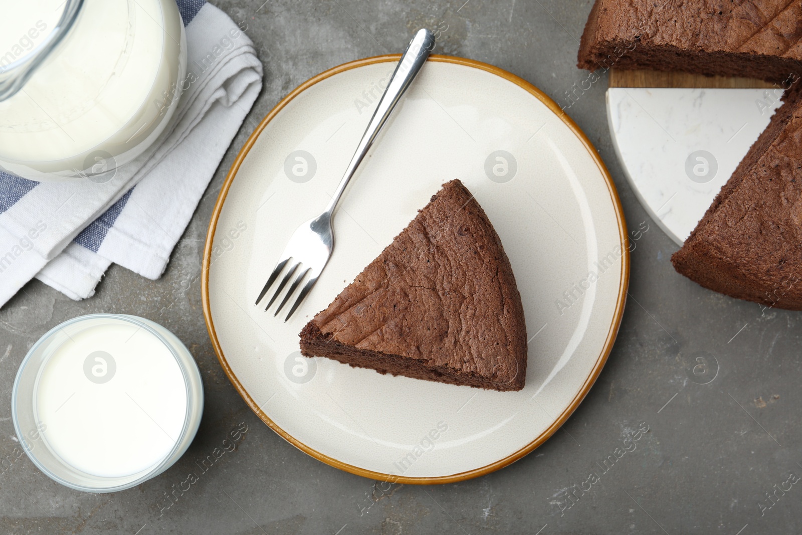 Photo of Piece of tasty chocolate sponge cake served on grey table, flat lay