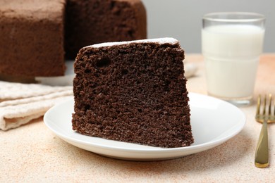 Photo of Piece of tasty chocolate sponge cake served on light table, closeup