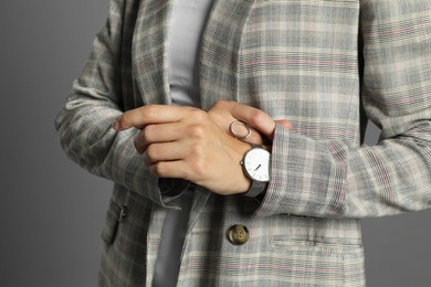 Beautiful woman with stylish jacket and watch on grey background, closeup