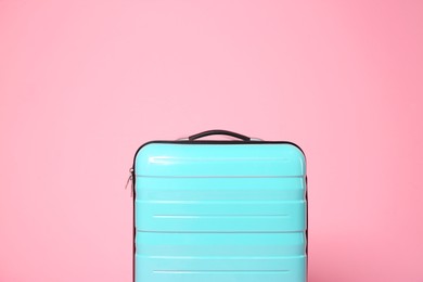 Photo of One new turquoise suitcase on pink background