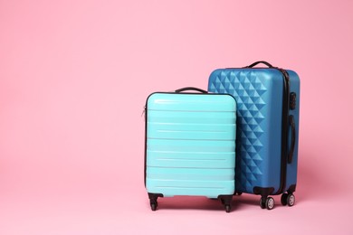 Photo of Two new color suitcases on pink background, space for text